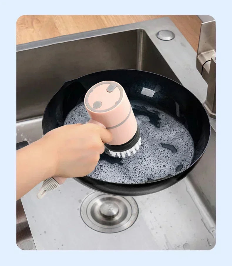 Hand using electric scrubber to clean soapy frying pan in kitchen sink